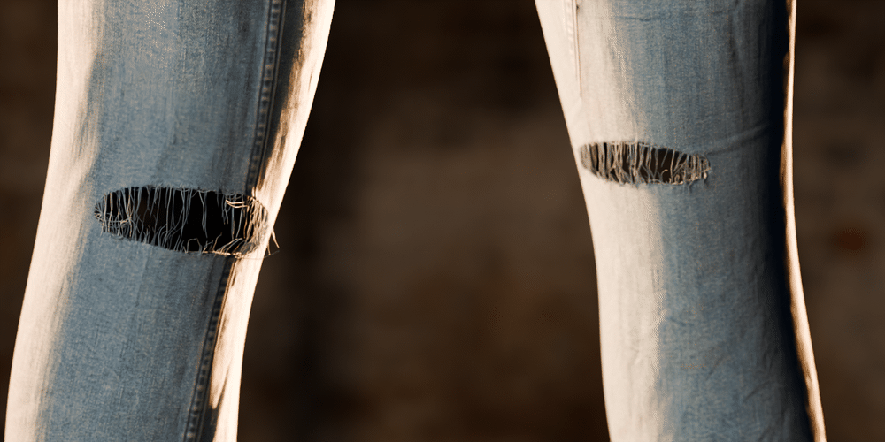 Both knees of a pair of jeans rip open; white threads stretch across the holes