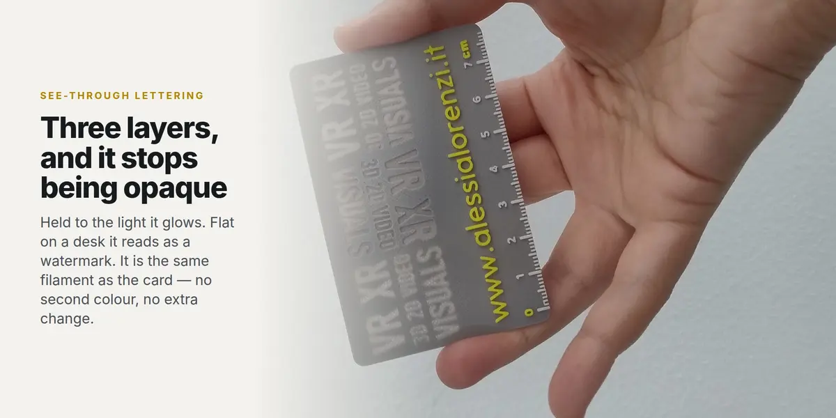 A printed grey card held in a hand, the hollowed-out lettering glowing against the light