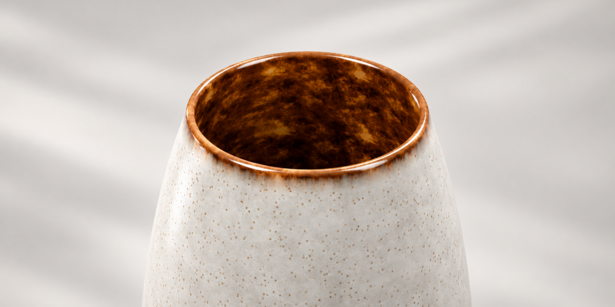 Close-up of amber brown glazed opening on the tall cream ceramic vase